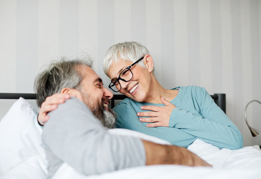 senior coule lying down in bed having fun laughing