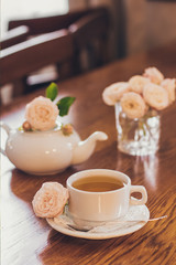 Beautiful fresh roses near a cup of tea and a in pastel tones romantic mood