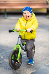 Happy little boy riding a run-bike in the park