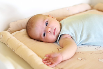 Newborn baby girl is lying on changing table.