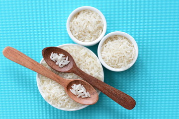 Natural raw white rice grains, on display in bowl and wooden spoon