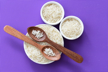 Natural raw white rice grains, on display in bowl and wooden spoon