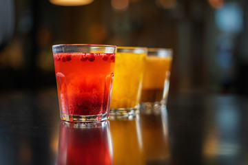 Hot drink with red berries on a black table against the background of other drinks.