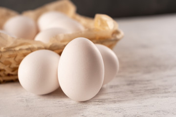 The egg near the square wicker basket on a light wooden surface. Close up.