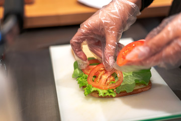The girl makes a vegetarian sandwich, puts a tomato on the bread.