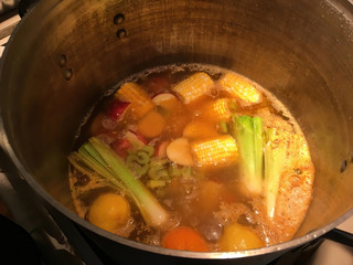 Vegetable soup with corn, leeks, potatoes, celery and tomatoes boiling in a large pot