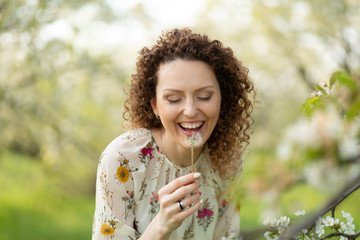 Obraz premium Pretty girl blowing dandelion in summer park. Green grass beautiful nature. Pure emotion.