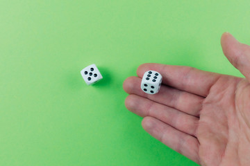 close-up of hand of man rolling dices on green table, being lucky and winning concept