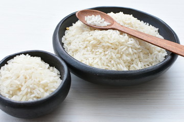Natural raw white rice grains, on display in bowl and wooden spoon