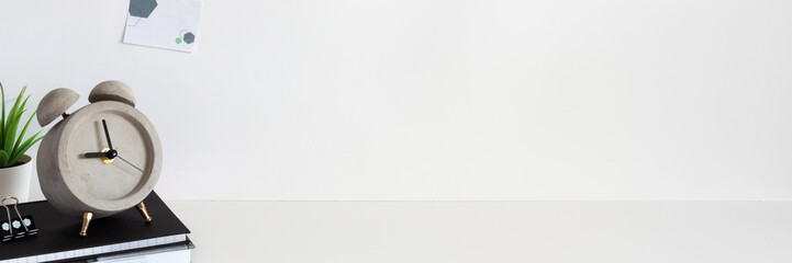 School desk against an empty white wall. Copy space. Books, succulent and alarm clock.Sticky note....