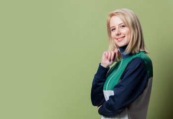 Beautiful blonde woman in 90s sport suit on green background