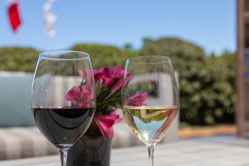 glasses of red wine on wooden table in garden