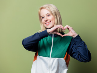 Beautiful blonde woman in 90s sport suit show Love gesture
