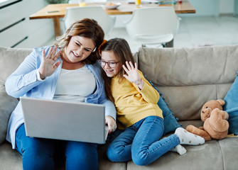 Mother and daughter wave to webcam on laptop