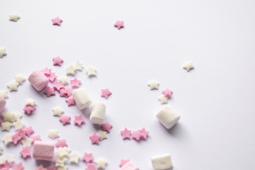 Sugar stars and marshmallows for baking decorations in pink and white colours. White background with copy text space