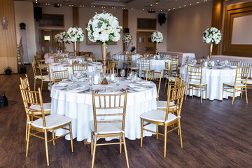 Table at a luxury wedding reception. Beautiful flowers on the table. Serving dishes, glass glasses, waiters work.