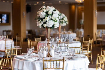 Table at a luxury wedding reception. Beautiful flowers on the table. Serving dishes, glass glasses, waiters work.