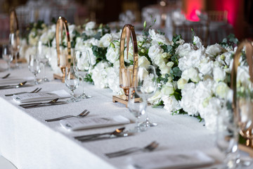 Table at a luxury wedding reception. Beautiful flowers on the table. Serving dishes, glass glasses, waiters work.