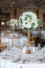 Table at a luxury wedding reception. Beautiful flowers on the table. Serving dishes, glass glasses, waiters work.