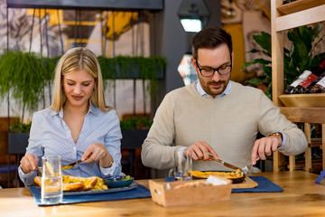 Happy couple at restaurant eating lunch, having fun.