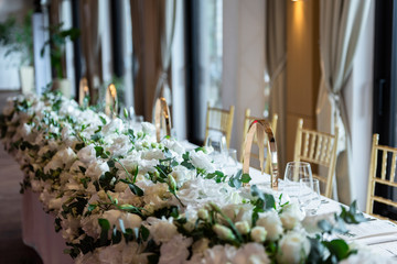 Table at a luxury wedding reception. Beautiful flowers on the table. Serving dishes, glass glasses, waiters work.
