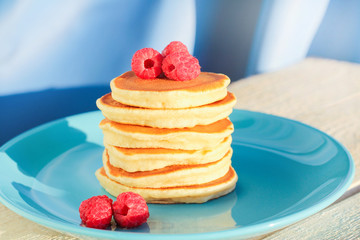 a stack of freshly baked pancakes decorated with raspberries. copcept delicious breakfast