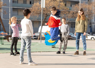 Happy smiling little friends playing with chinese jumping rope at playground