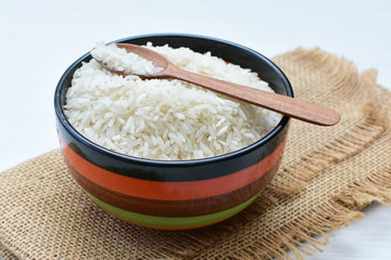 Natural raw white rice grains, on display in bowl and wooden spoon