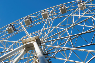 Ferris wheel on background of blue sky in sunny summer day, bottom view.