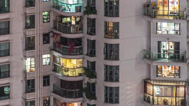 Panning apartment windows in downtown time lapse. Timelapse of residential flats windows lighting up and turning off overnight in Shenzhen, China. Modern life in crowded massive apartment buildings.