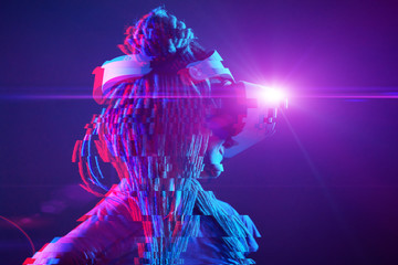 Woman is using virtual reality headset. Neon light studio portrait. Image with glitch effect.