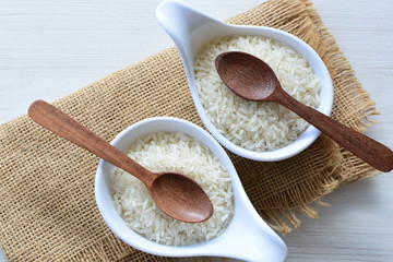 Natural raw white rice grains, on display in bowl and wooden spoon