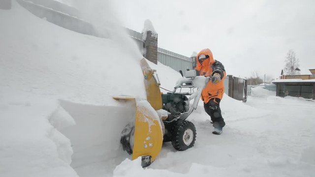 Man cleans snow with a snow thrower. Pushing mashine