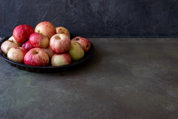 Fruits -rustic apples on a platter on a dark background
