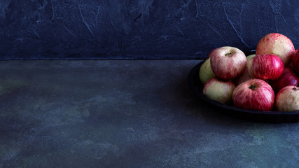 Fruits -rustic apples on a platter on a dark background