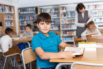 Fototapeta na wymiar Іmiling boy reading in school library