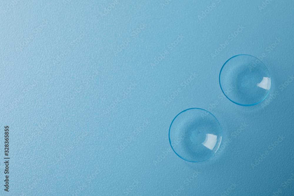 Sticker contact lenses on blue background, space for text