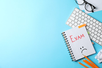 Inscription Exam, keyboard and stationary on blue background, top view