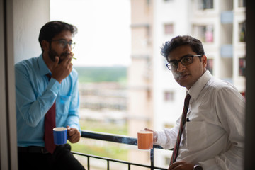 Corporate meetings with coffee/tea  and cigarette between young and energetic Indian Bengali bosses/officers/managers at balcony of the office building regarding a project. Indian corporate lifestyle