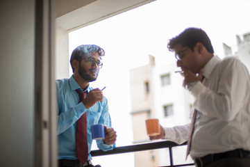 Corporate meetings with coffee/tea  and cigarette between young and energetic Indian Bengali bosses/officers/managers at balcony of the office building regarding a project. Indian corporate lifestyle