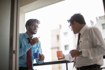Corporate meetings with coffee/tea  and cigarette between young and energetic Indian Bengali bosses/officers/managers at balcony of the office building regarding a project. Indian corporate lifestyle