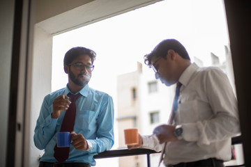 Corporate meetings with coffee/tea  and cigarette between young and energetic Indian Bengali bosses/officers/managers at balcony of the office building regarding a project. Indian corporate lifestyle