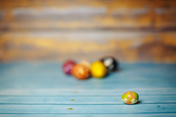 Easter colored painted small egg on blue and brown blurry wooden background