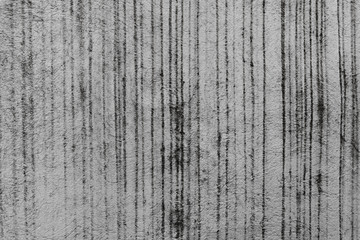 A close-up shot of a grungy gray concrete wall with striped humid tracks from rain