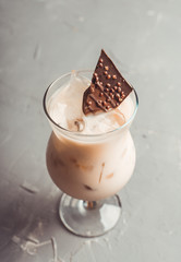 Creamy cocktail with ice and slice of chocolate. Selective focus. Shallow depth of field.