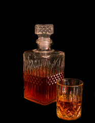 Decanter glass with drink against black background