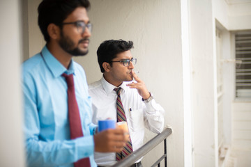 Corporate meetings with coffee/tea between young and energetic Indian Bengali bosses/officers/managers and secretary at balcony of the office building regarding a project. Indian corporate lifestyle