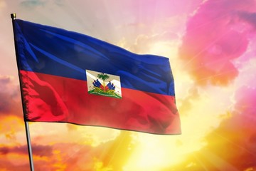 Fluttering Haiti flag on beautiful colorful sunset or sunrise background. Success concept.