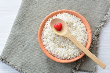 Natural raw white rice grains, on display in bowl and wooden spoon