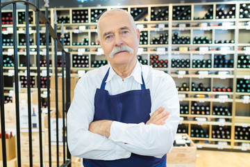 smiling senior seller man in wine store